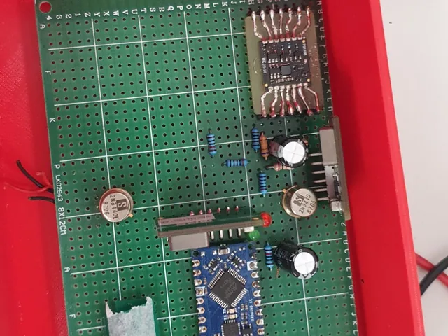 The stand&rsquo;s firing controller, built with the students on perfboard in a red 3D-printed enclosure: an Arduino Nano, metal-can transistors and a surface-mount module hand-wired onto an adapter.