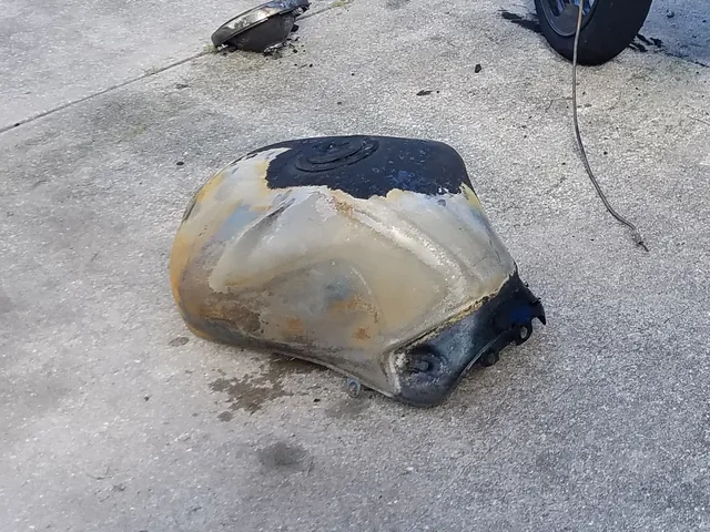 The fuel tank the day after the fire, lying on the driveway: paint burned off, metal scorched and discoloured.