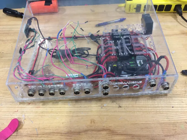 The robot&rsquo;s electronics box: a clear acrylic case engraved &ldquo;NASA RMC at Florida Tech, PHRED&rdquo;, with motor controllers, wiring and labelled circular connectors.