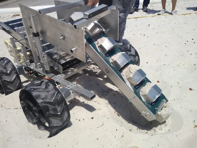 The aluminium mining robot in a sand pit, its bucket-ladder digging arm lowered into the sand, buckets full.