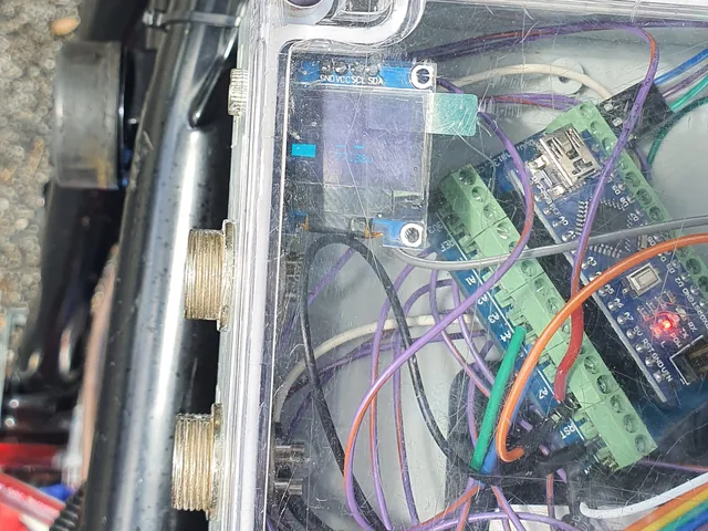 A clear enclosure on the bike holding Arduino Nano boards on screw-terminal breakouts, an OLED display and CAN wiring.