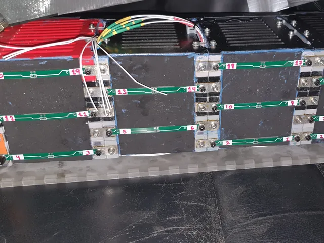 Four 18650 battery modules side by side on a clear tray, with green cell-tap strips hand-numbered 0 to 20.