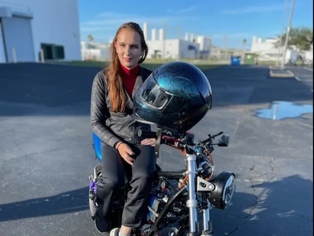 Me sitting on the finished electric motorcycle in a parking lot, my helmet resting on the mirror.